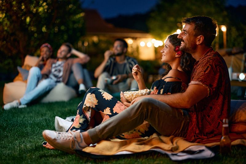 Happy couple watching movie with friends in the backyard at night.