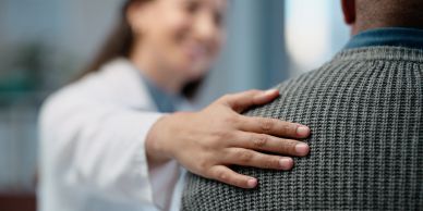 Doctor comforting a patient with a hand on their shoulder.