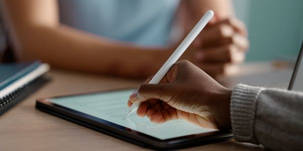 Person writing on a tablet with a stylus.