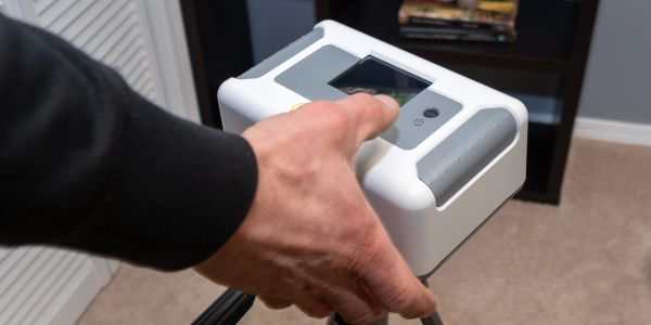 A hand operating a scientific device with a screen.