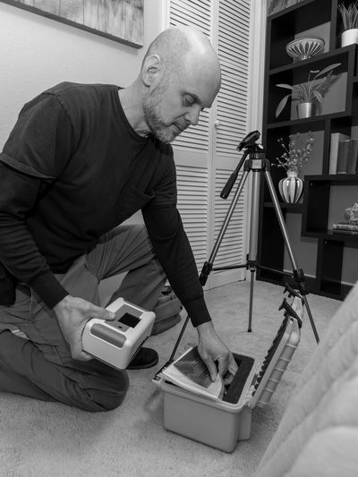 Man organizing air quality gear and photos near a tripod.