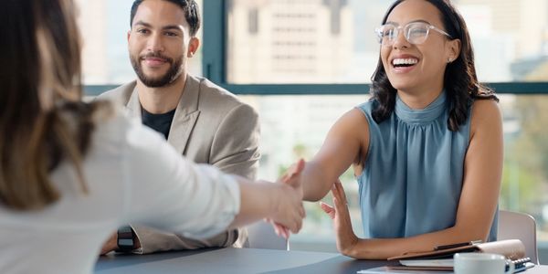 Two professionals smiling and shaking hands in a business meeting.