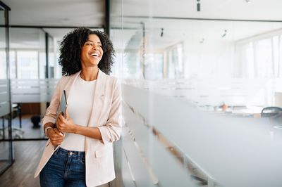Smiling woman in casual business attire standing in a bright office.
