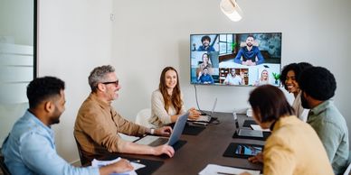 A hybrid meeting with participants both in-person and via video call.