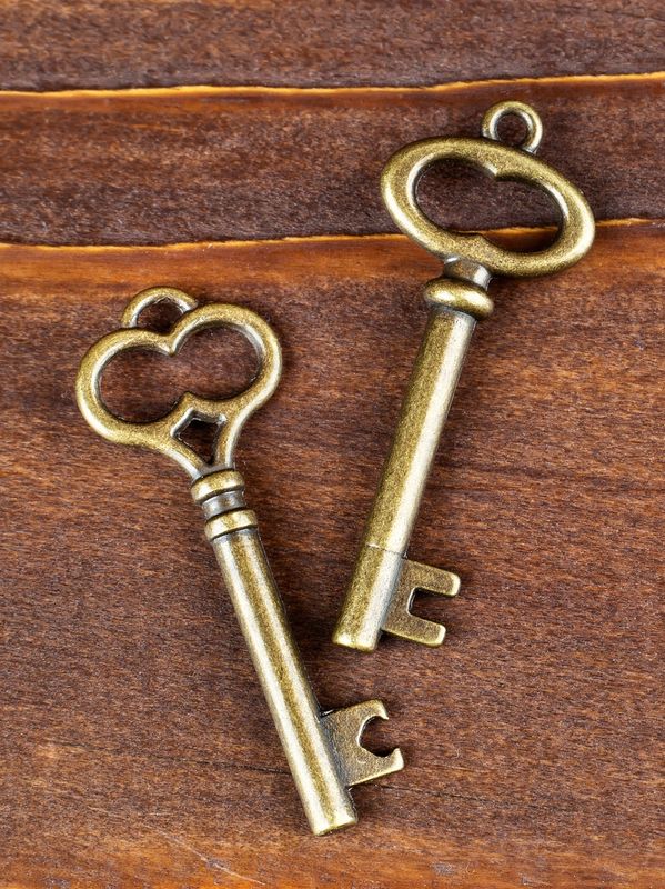Two vintage brass keys lying on a wooden surface.