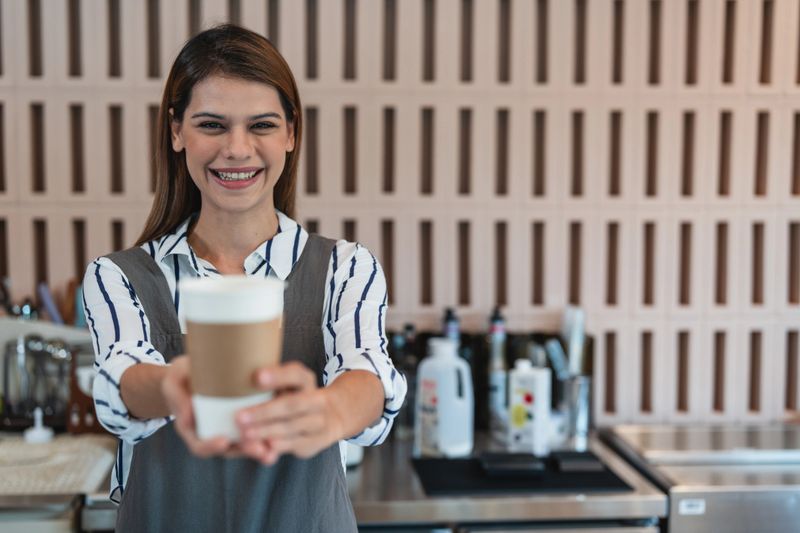 Image of a coffee shop owner serving coffee to customers at the counter. small business owner Have a passion for service, views from customers.