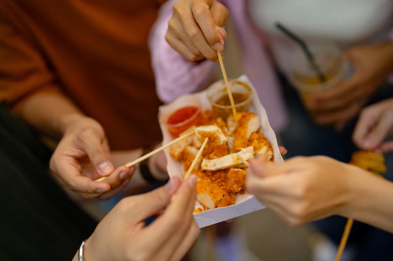 Portrait of Asian group of friends enjoying delicious street food at the street food festival in Bangkok.