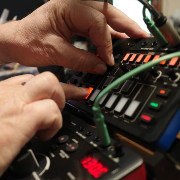 Hands adjusting knobs on an electronic music device.