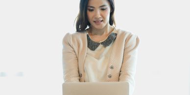 A woman working on a laptop in a bright setting.