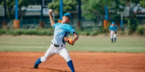 Young baseball pitcher throwing a ball on the field during a game.