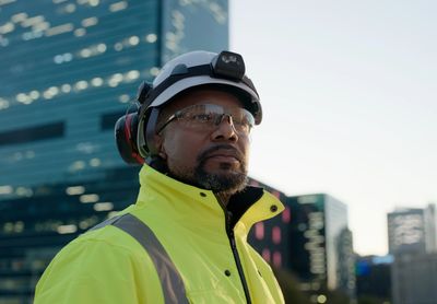 Construction worker in safety gear at a city site.