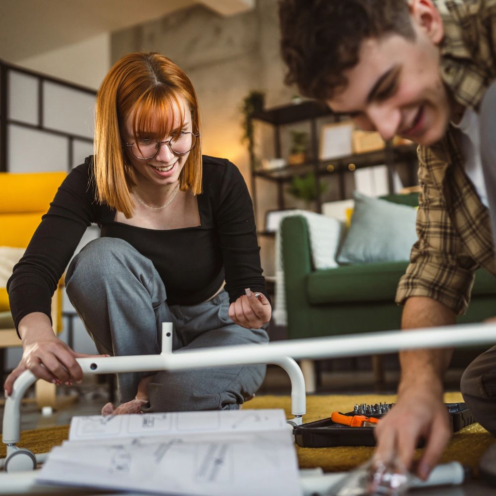 Young couple happily assembling furniture together at home.