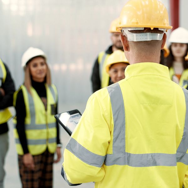Construction leader giving instructions to a diverse team wearing safety gear.