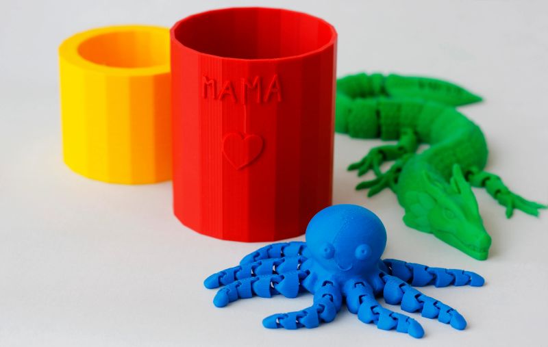 Collection of four bright colorful plastic products created by a child using a 3d printer. Variety of plastic products manufactured by 3D printing on white background.