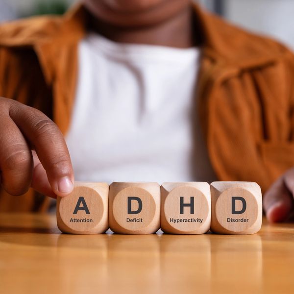 Child arranging blocks spelling ADHD with descriptive words.