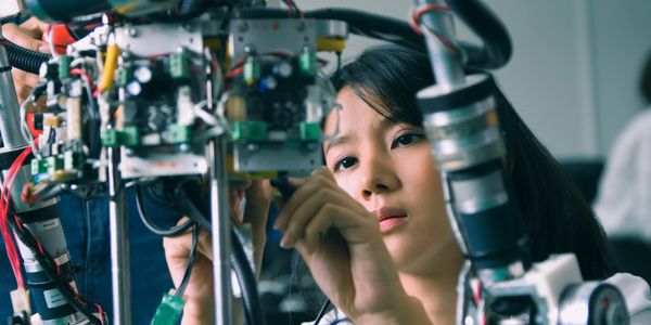 Woman engineers assembling and repairing a complex robotic device.