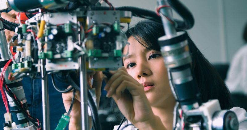 Two students collaborate intently in a high-tech robotics lab, exemplifying teamwork in scientific innovation and education.