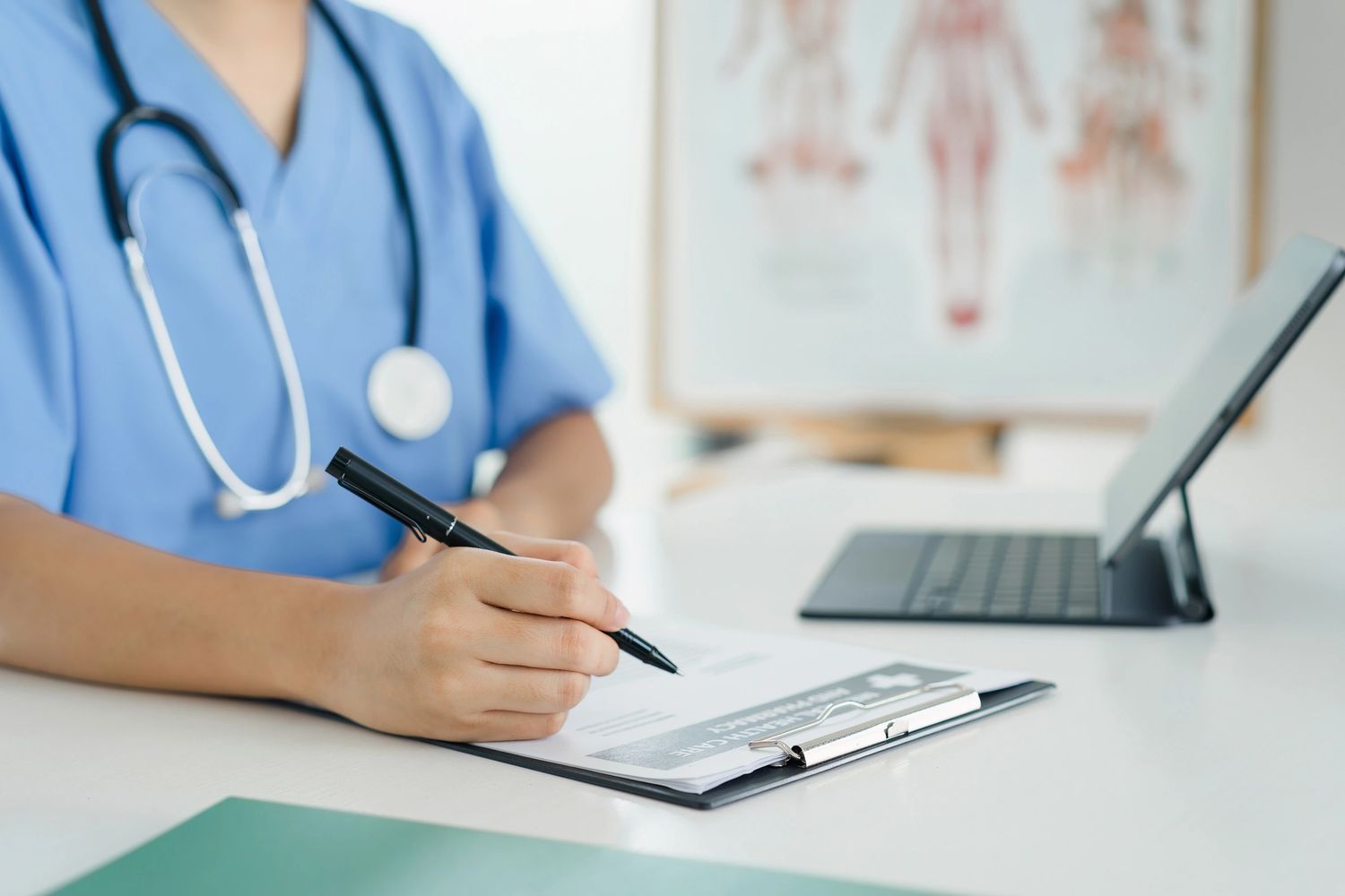 Healthcare professional writing on a clipboard with a stethoscope around their neck.