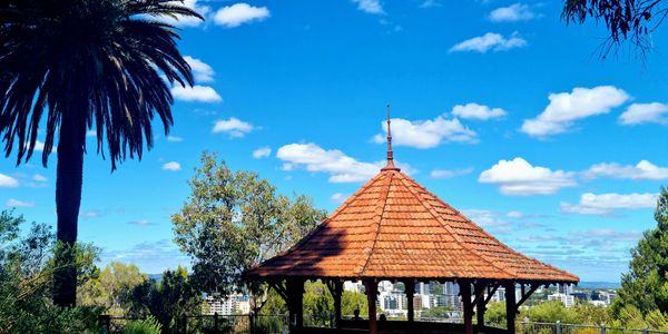 Gazebo with a tiled roof under a blue sky and palm tree.