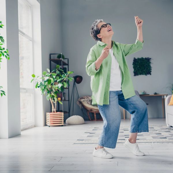 Woman dancing joyfully in bright living room.