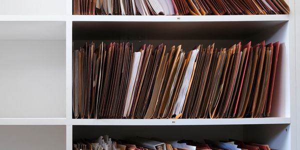 Shelves filled with organized folders and documents in a white storage unit.