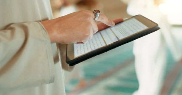 Person reading from a digital tablet with Arabic text.