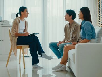 Couple having a serious conversation with a counselor in a bright room.