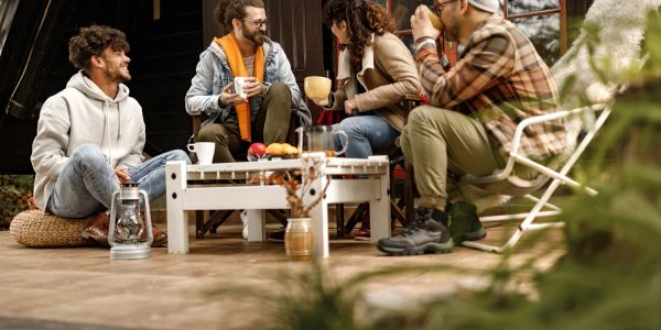Group of friends enjoying drinks outdoors on a porch.