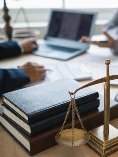 Books, scales of justice, and a laptop on a lawyer's desk.