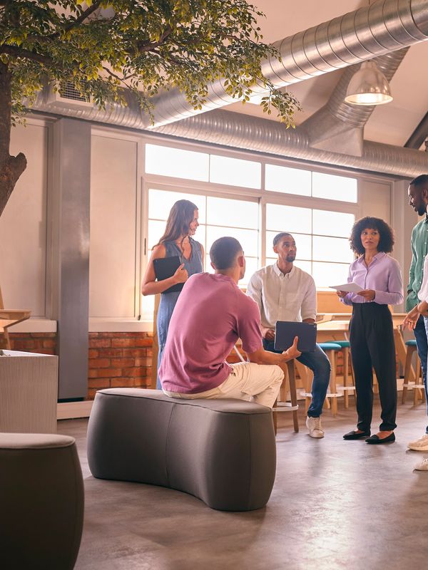 A group of young professionals engaged in a casual meeting in a modern office space.
