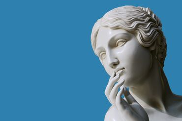 Close-up of a classical marble statue's face and hand.