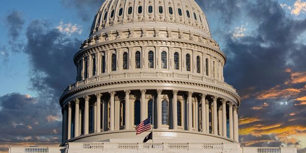 The U.S. Capitol dome at sunset with flags.