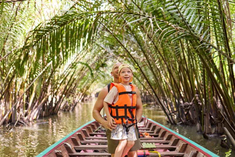 A little boy with a life jacket goes on a trip with his father on a canal with a longtail boat in Thailand