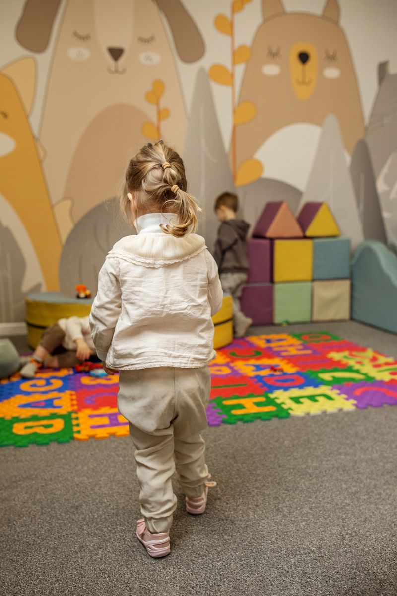 Toddler is completely absorbed in her play, surrounded by colorful toys in vibrant and educational playroom.
