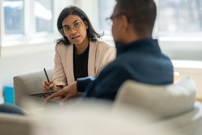 A woman attentively listens to a man during a conversation in a bright room.