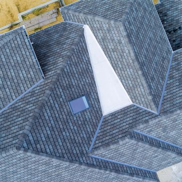 Aerial view of a grey tiled roof with a small skylight.