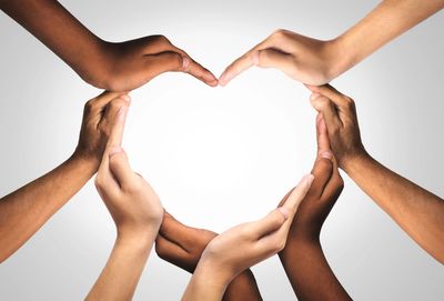 Diverse hands forming a heart shape together symbolizing unity and love.