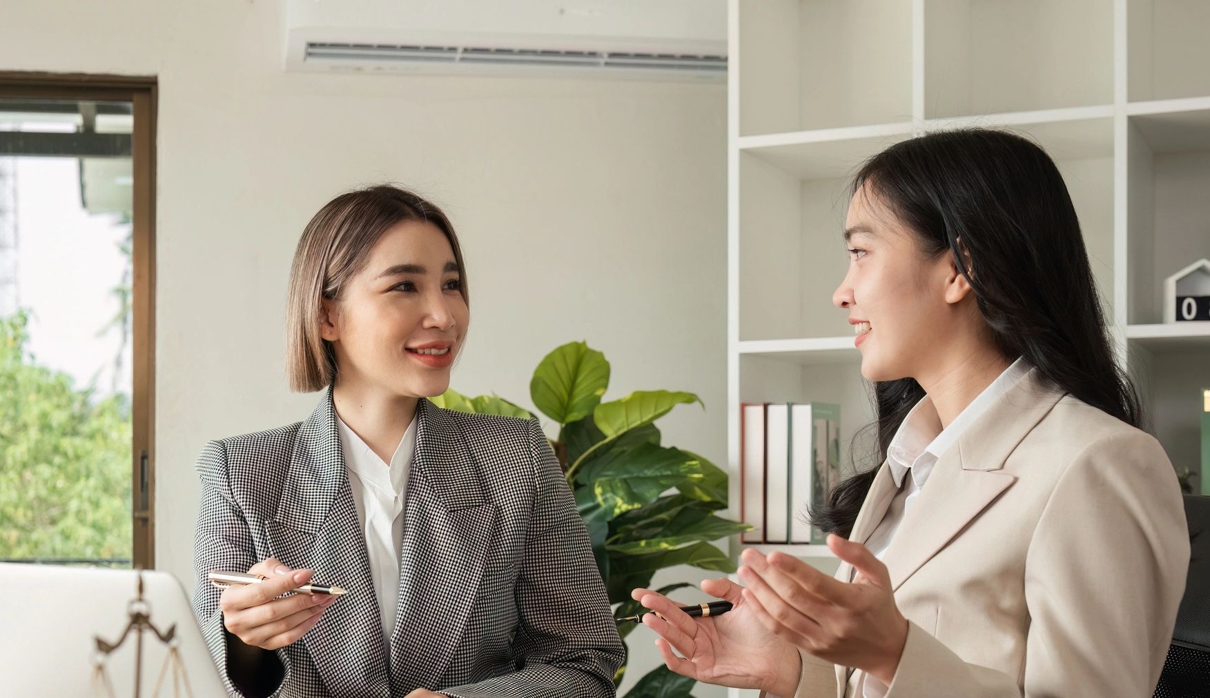 Two women in business attire having a positive discussion in an office.