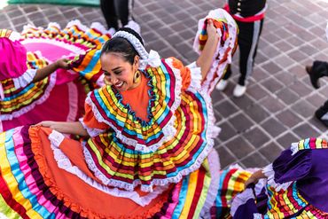 Woman joyfully dancing in vibrant traditional Mexican dress.