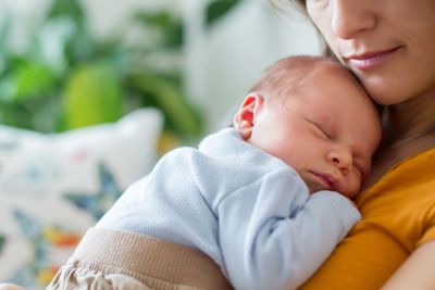 A newborn baby peacefully sleeping on a mother's chest.