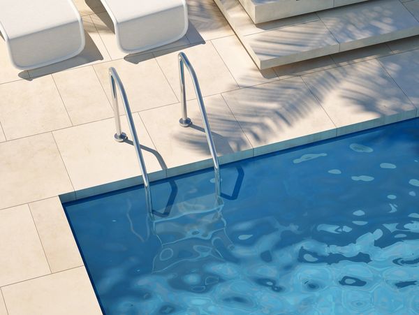 Modern poolside with white loungers and clear blue water.