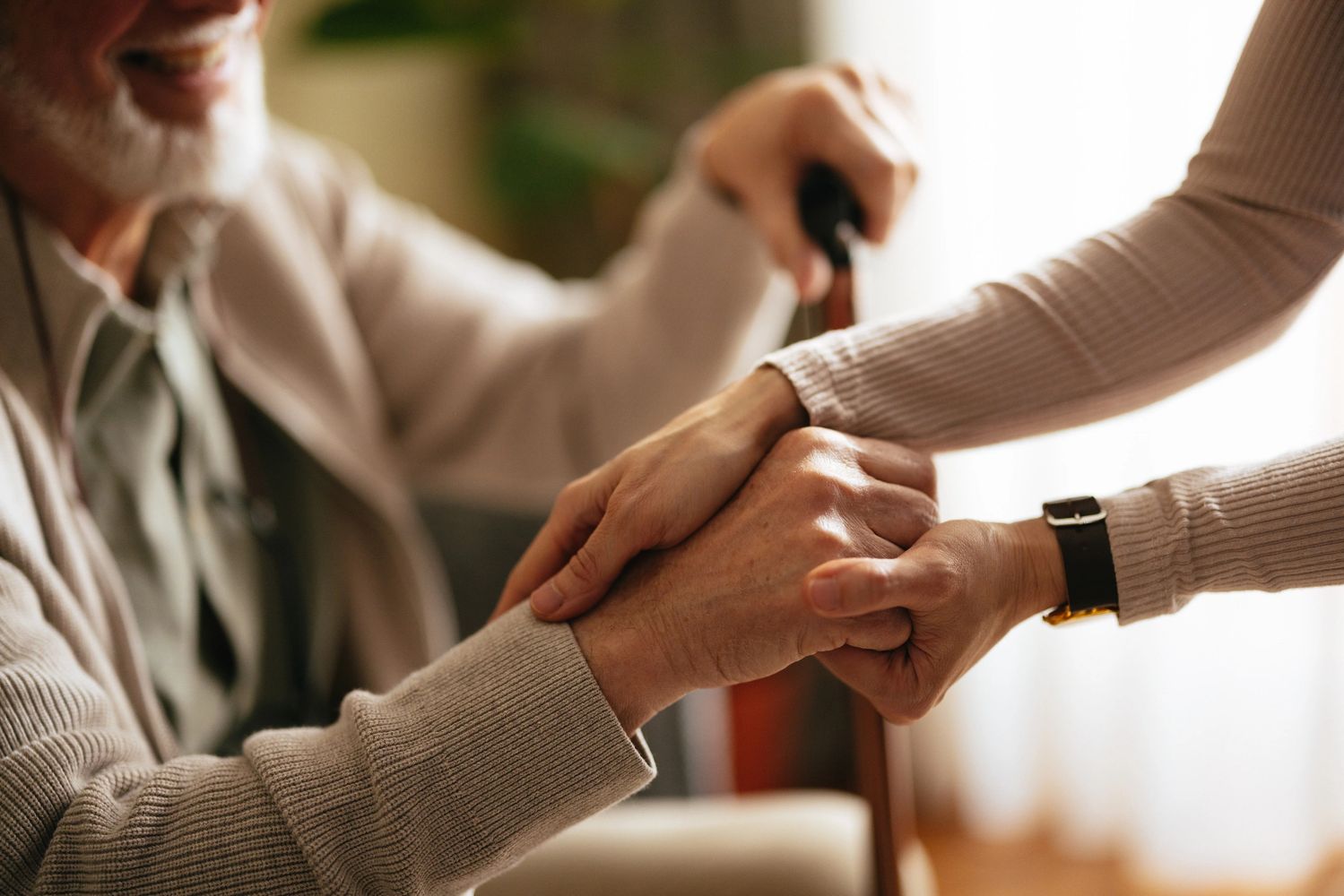 An elderly man holding hands with a caregiver, showing care and support.