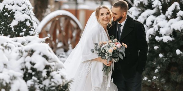 A joyful bride and groom pose together in a snowy outdoor setting.