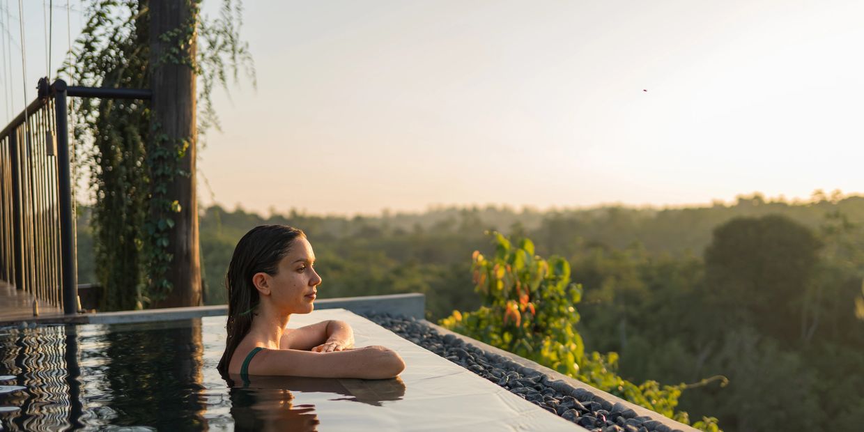 A lady standing in an infinity pool enjoying the view