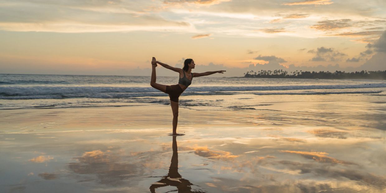 Person doing yoga on the beach at sunset.