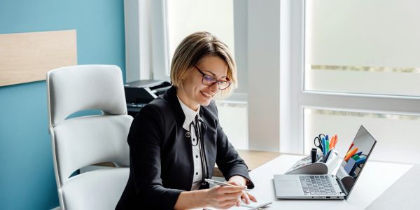 Woman working happily at her desk with a laptop.