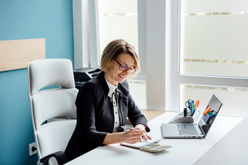 Successful female accountant/businesswoman making financial calculations in her office