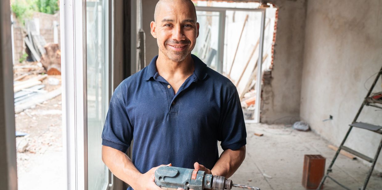 Man holding a drill inside a construction site.