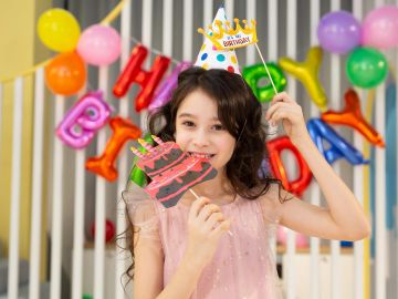 Smiling girl celebrating birthday with colorful decorations and props.