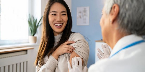 Young woman receiving a vaccine shot and smiling.